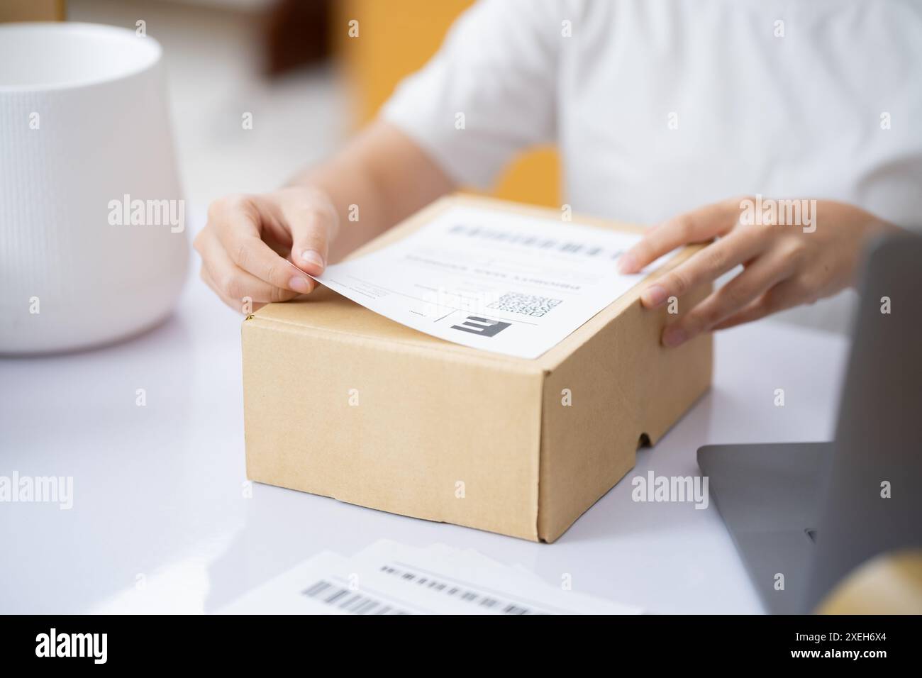 Le commerce des achats en ligne. Fixation de l'étiquette d'expédition à un colis. Banque D'Images