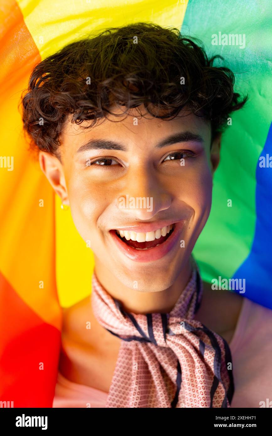 Jeune homme souriant avec un drapeau arc-en-ciel célébrant la fierté et la diversité LGBTQ+ Banque D'Images