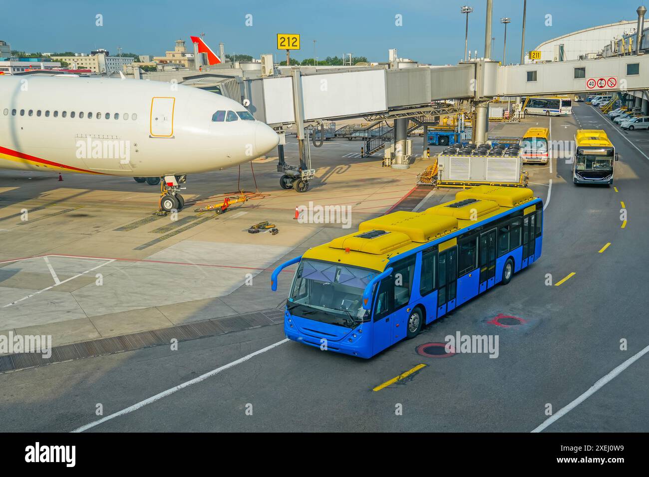 Vue sur le tablier d'un important centre de transport aéroportuaire. Un avion de ligne large est attaché au terminal, un bus avec passagers passe pour monter à bord du Banque D'Images