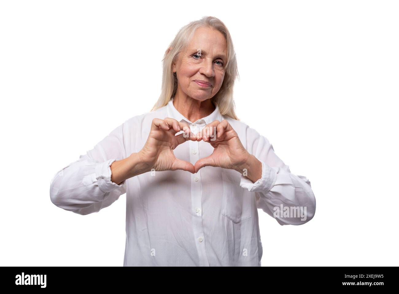 Une femme d'affaires âgée avec les cheveux gris dans une chemise montre un cœur Banque D'Images