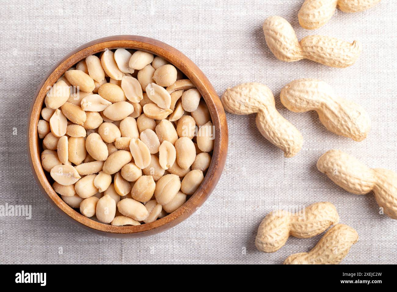 Cacahuètes grillées et salées dans un bol en bois sur tissu de lin. Snack prêt-à-manger, à base de fruits d'Arachis hypogaea, également connu sous le nom d'arachide. Banque D'Images