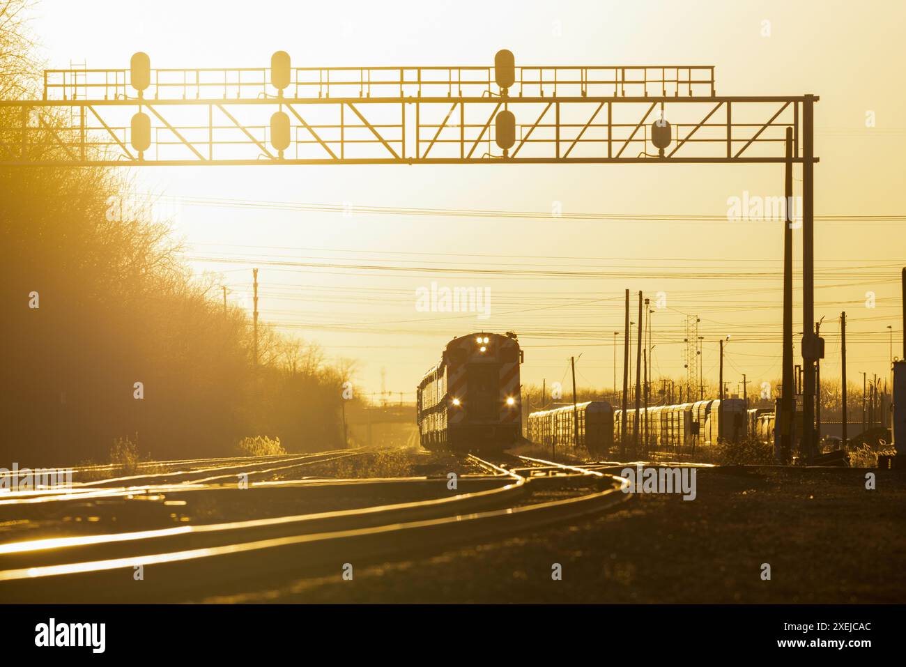 Trains et voies avec pont de signalisation au coucher du soleil Banque D'Images