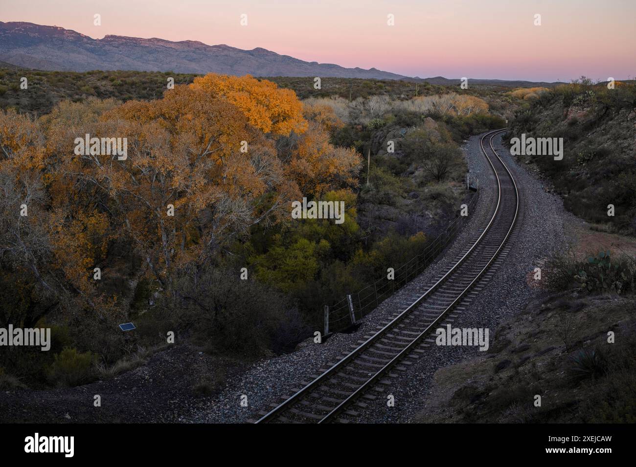 Une voie ferrée sinueuse qui recule dans un coucher de soleil coloré Banque D'Images