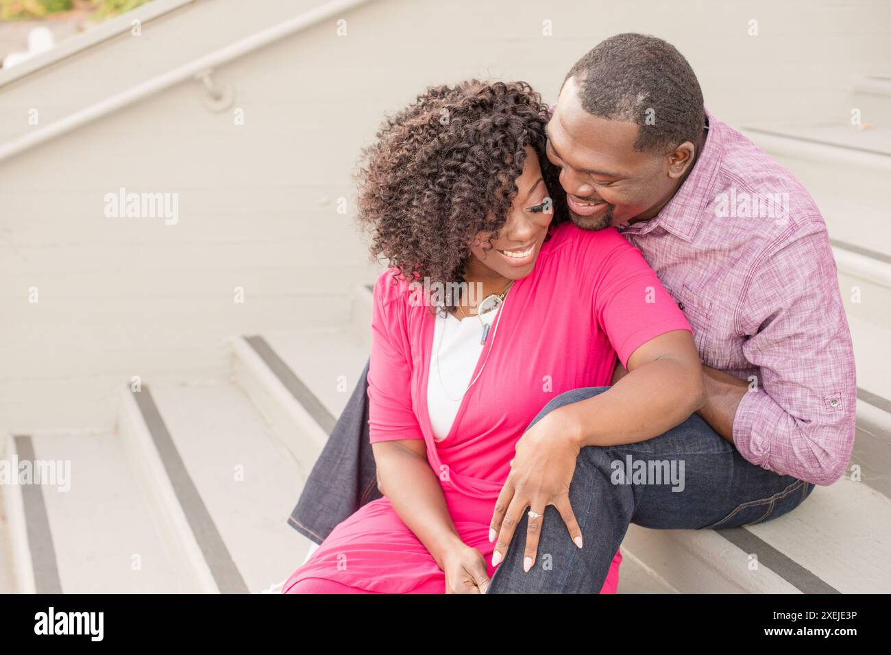 Couple assis sur les marches riant ensemble Banque D'Images
