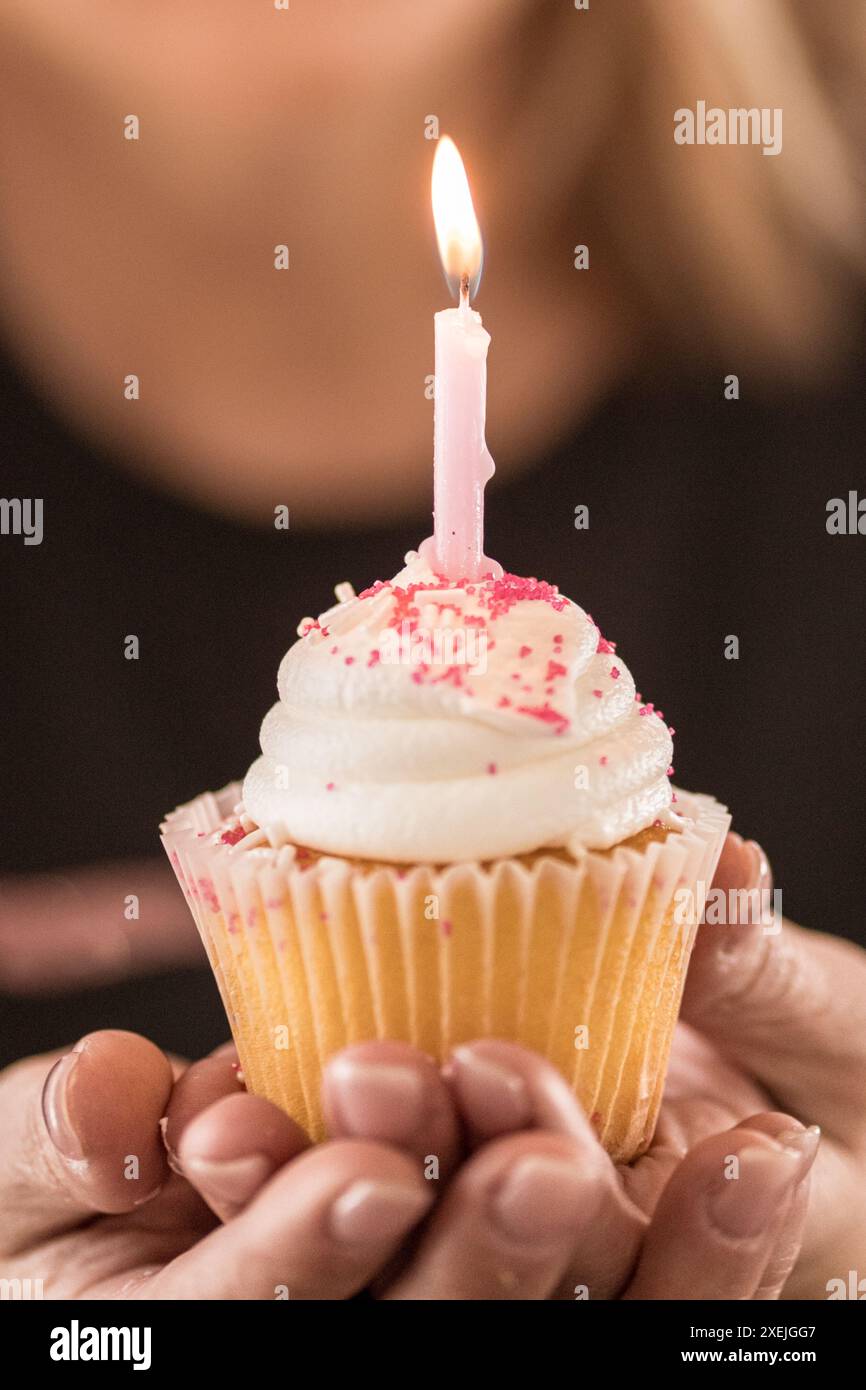 Gros plan d'une bougie d'anniversaire allumée avec une dame en arrière-plan Banque D'Images