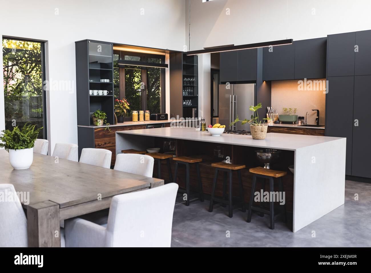 Cuisine moderne avec grand îlot, tabourets de bar et table à manger dans une maison contemporaine Banque D'Images