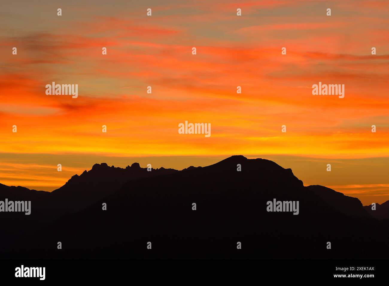 Ciel nocturne dramatique avec nuages brûlants et silhouette de paysage de montagne Banque D'Images