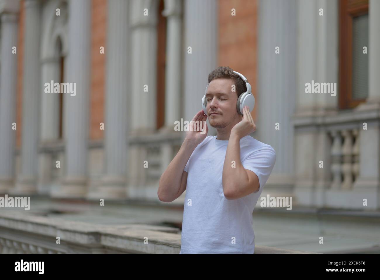 Un jeune homme avec une tablette dans les mains écoutant de la musique avec des écouteurs dans une rue de Vienne. Concept de style de vie de détente et de plaisir. Banque D'Images