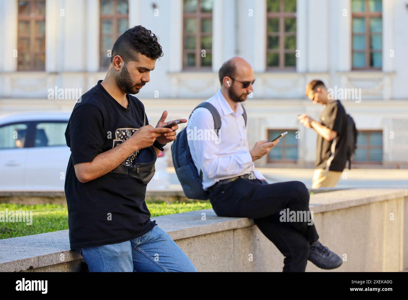 Hommes utilisant des smartphones dans la rue de la ville en été Banque D'Images