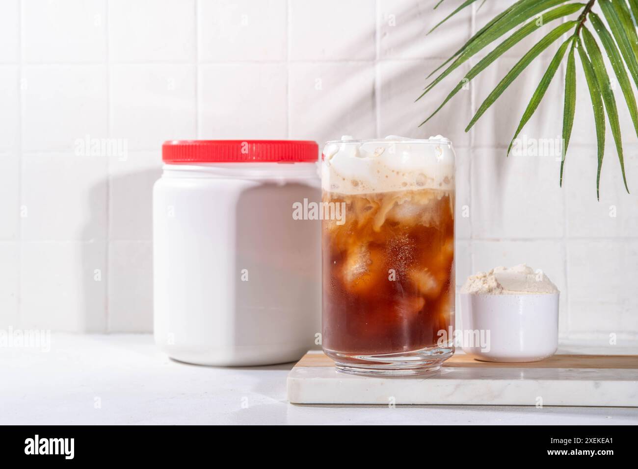 Verre de boisson au café latte collagène avec de la poudre de collagène dans un pot et une cuillère, sur une table de cuisine blanche. Supplément naturel pour la beauté, la santé de la peau, les os, Banque D'Images