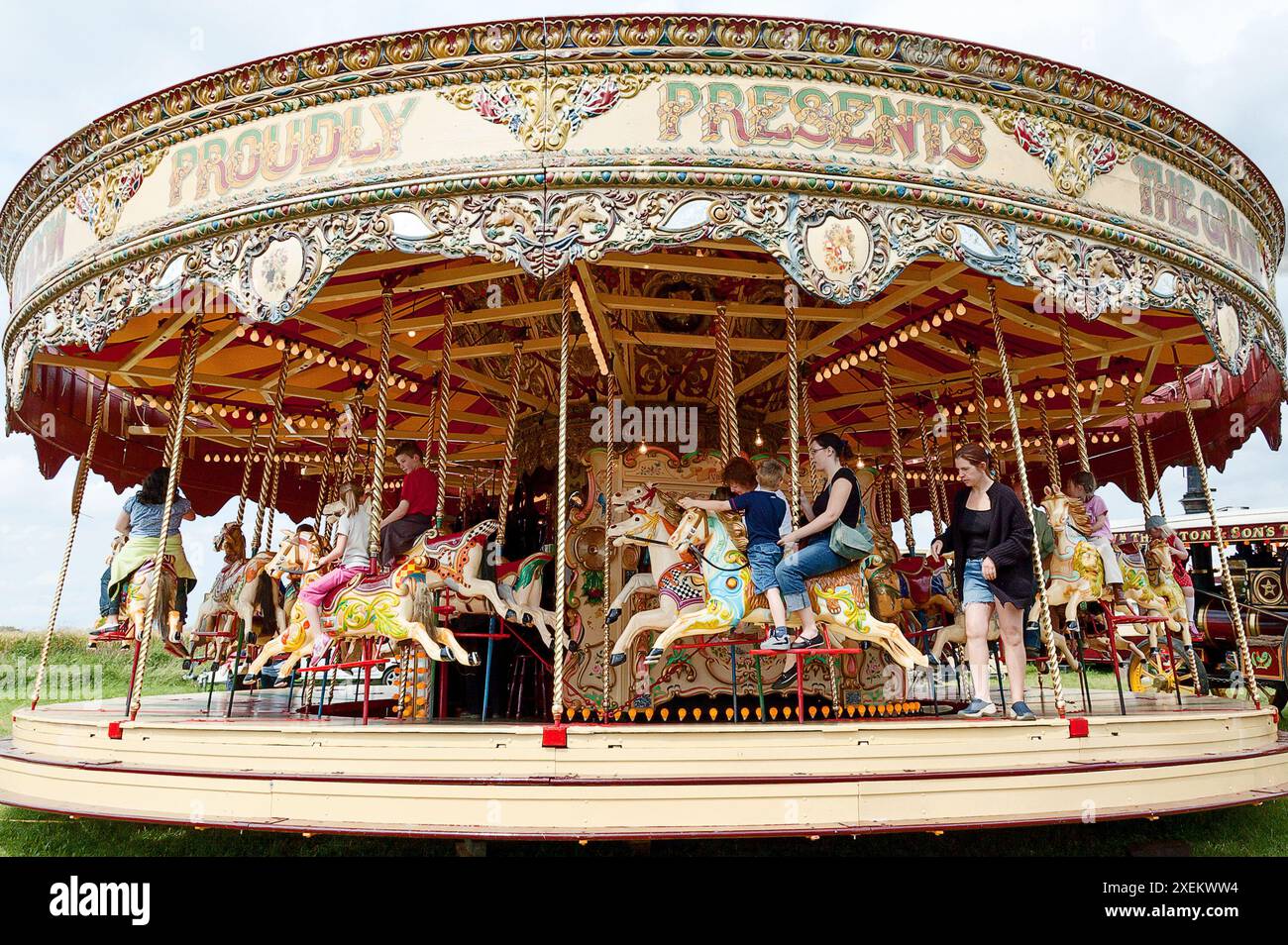 Les gens qui roulent sur un carrousel de chevaux galopants à vapeur Frederick Savage lors d'un spectacle de campagne dans le Yorkshire Banque D'Images