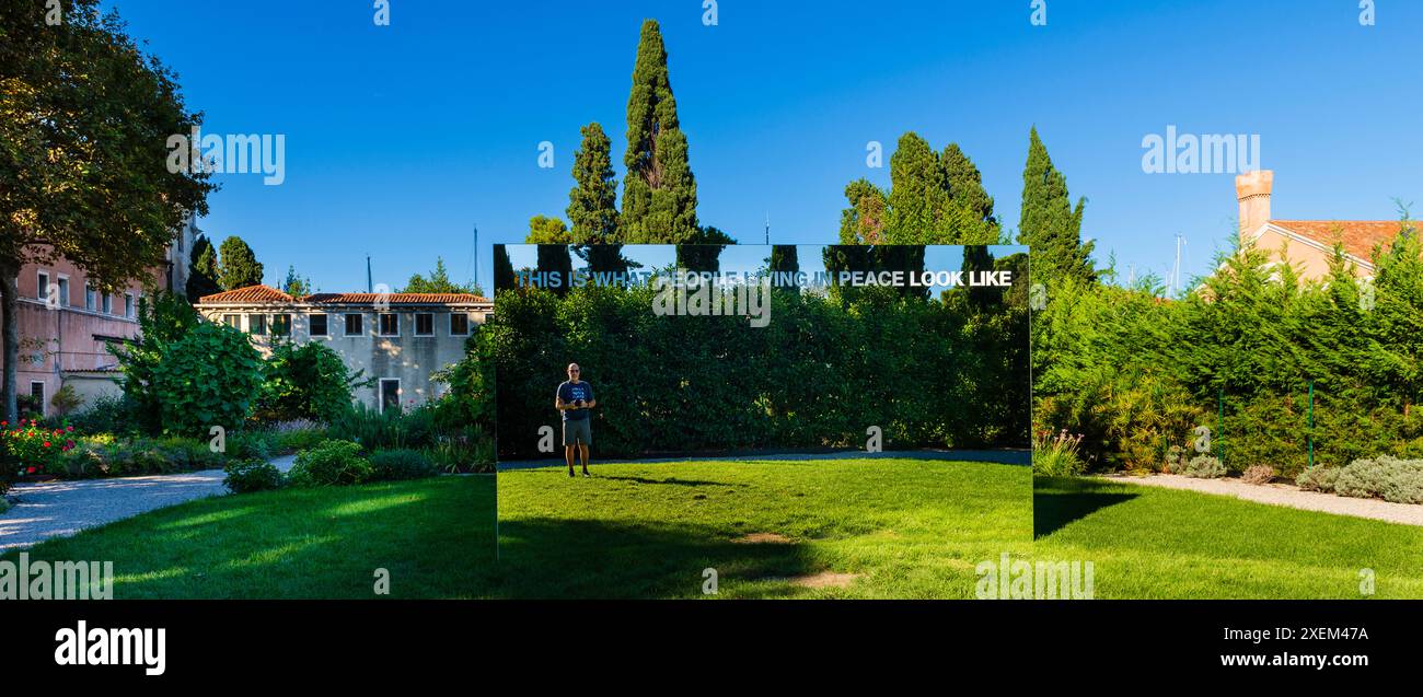 Touristes masculins regardant dans le miroir de la paix au jardin du monastère San Giorgio Maggiore à Venise ; Venise, Vénétie, Italie Banque D'Images