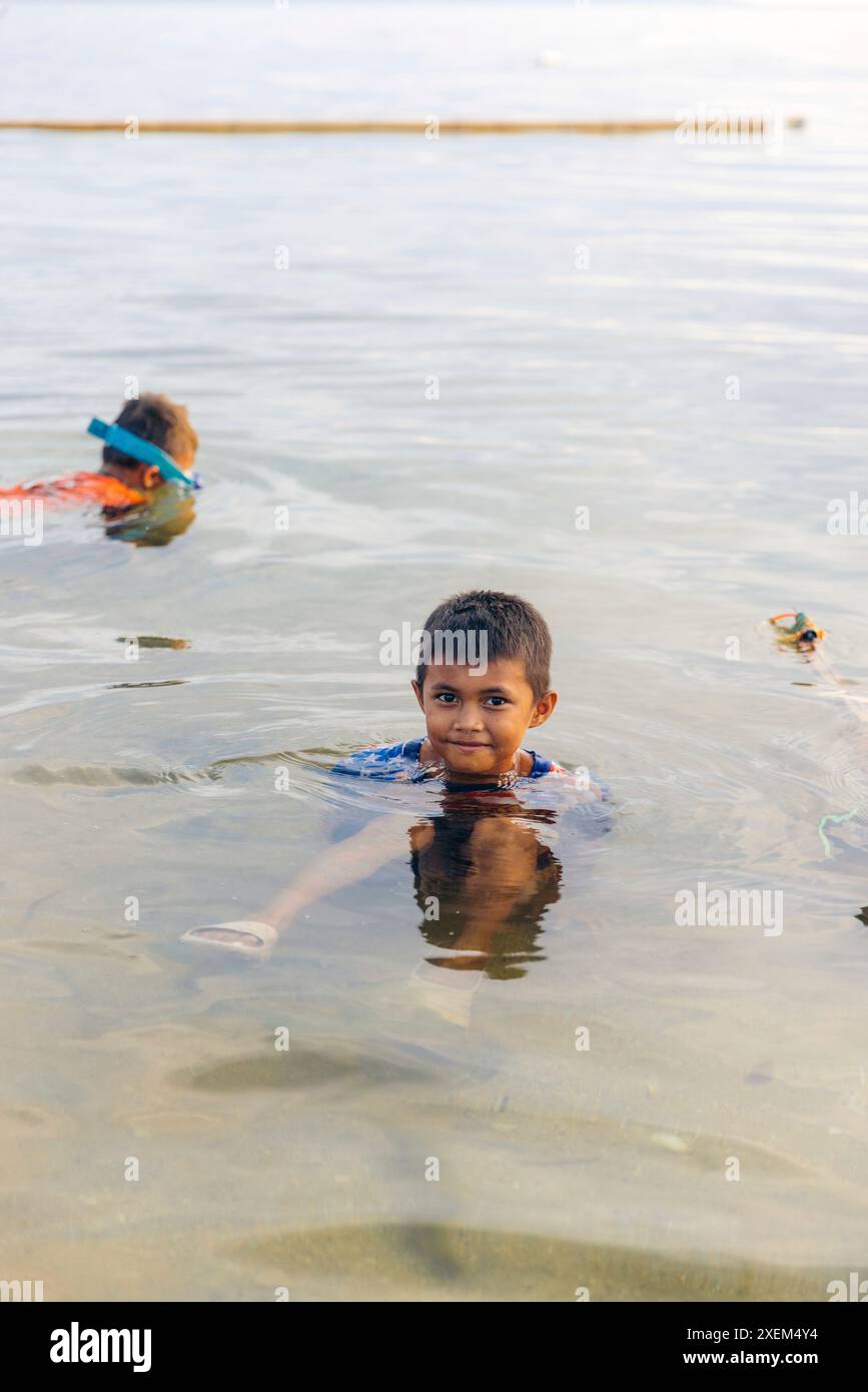 Enfants nageant dans l'eau claire de l'océan au large de l'île de Bunaken en Indonésie ; Bunaken, Sulawesi du Nord, Indonésie Banque D'Images