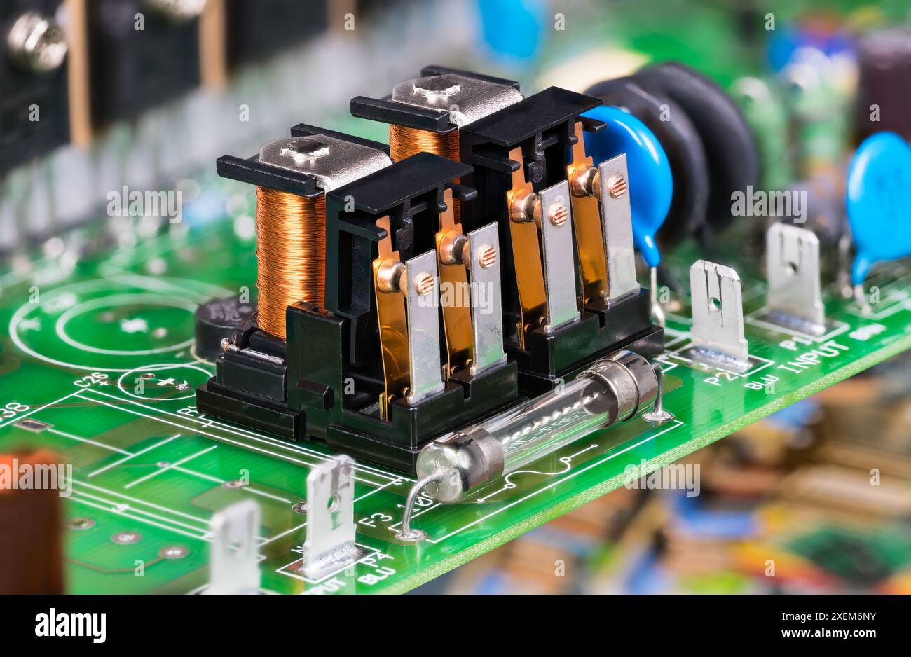 Composants électroniques comme relais électromagnétiques ou fusible électrique en verre sur PCB vert. Gros plan sur deux commutateurs électromécaniques avec bobine sur carte de circuit imprimé. Banque D'Images