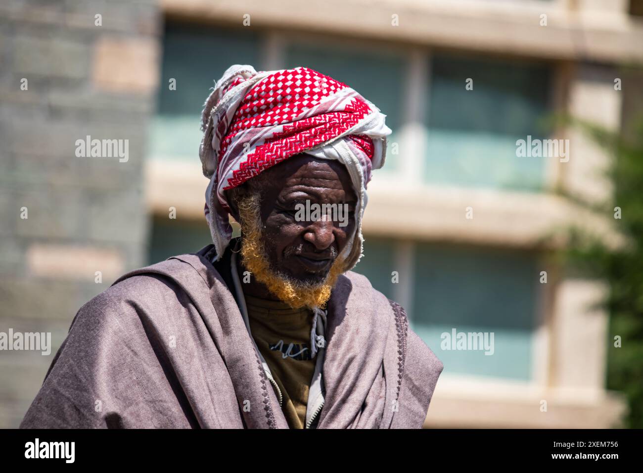 Un aîné somalien vivant dans la région d'Afar en Éthiopie, vêtu d'une tenue traditionnelle avec une écharpe rouge autour de sa tête et une barbe teinte au henné orange Banque D'Images