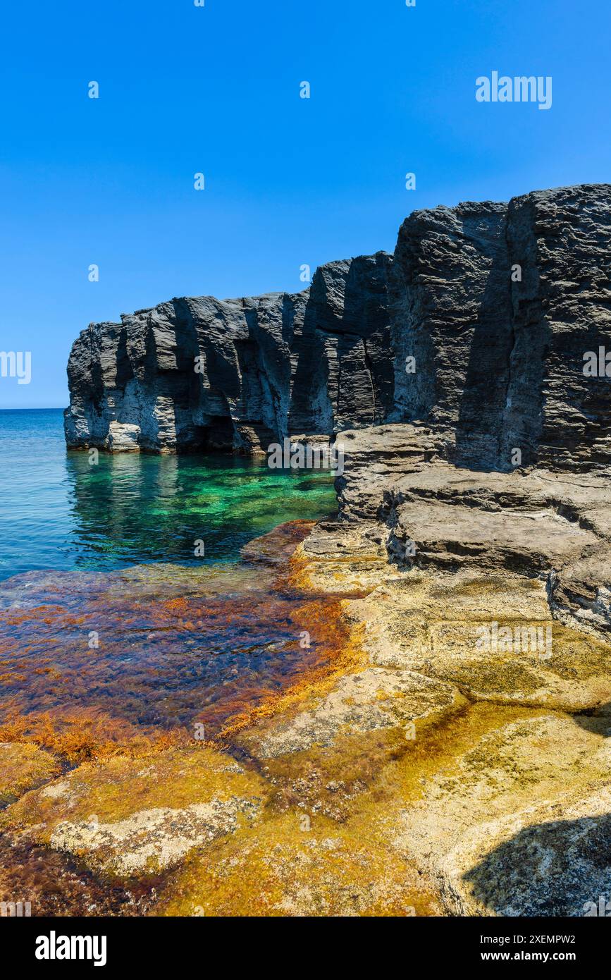 Vue rapprochée des falaises de roches volcaniques et du rivage à Cala del Bue Marino sur l'île de Pantelleria par une journée ensoleillée Banque D'Images