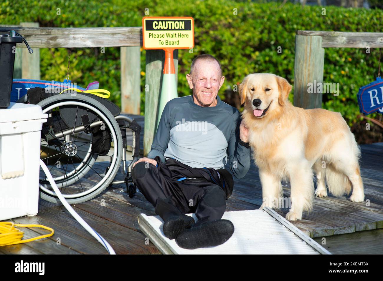 Homme paraplégique et son chien d'assistance sur un quai attendant d'embarquer sur un bateau ; Boynton Beach, Floride, États-Unis d'Amérique Banque D'Images