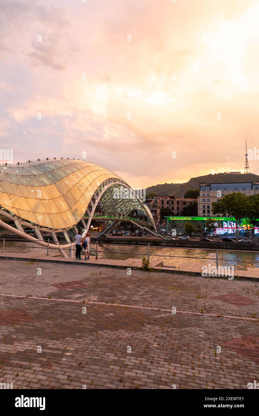 Tbilissi, Géorgie - 16 juin 2024 : le pont de la paix est un pont piétonnier en forme d'arc, une construction en acier et en verre au-dessus de la rivière Kura, reliant t Banque D'Images