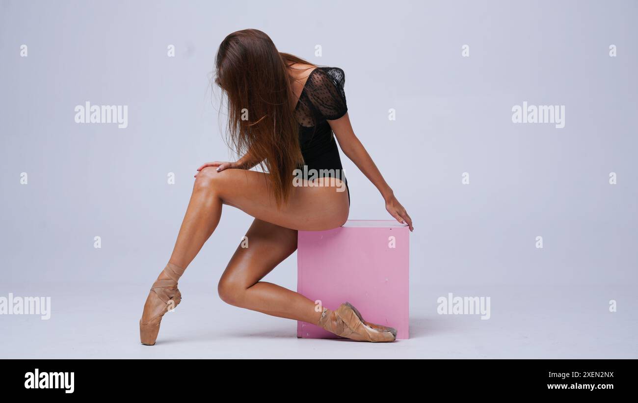 Ballerine en chaussures de pointe en studio sur chaise cube dans le style de la rue posant Banque D'Images