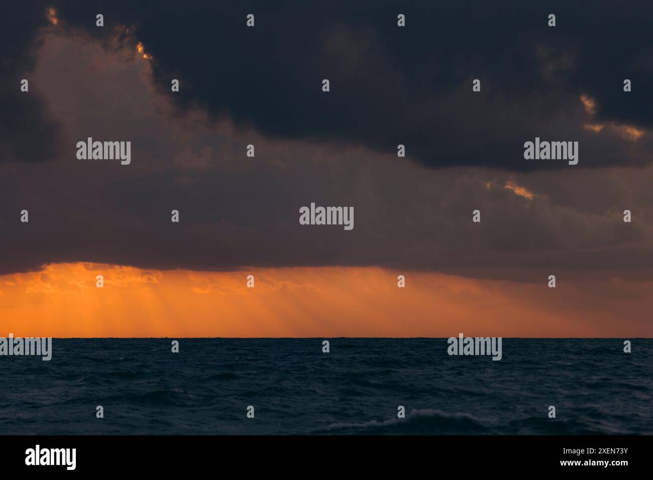 Des flux dorés de lumière provenant de nuages sombres créent un coucher de soleil spectaculaire sur l'océan à mai Khao Beach dans le nord de Phuket Banque D'Images