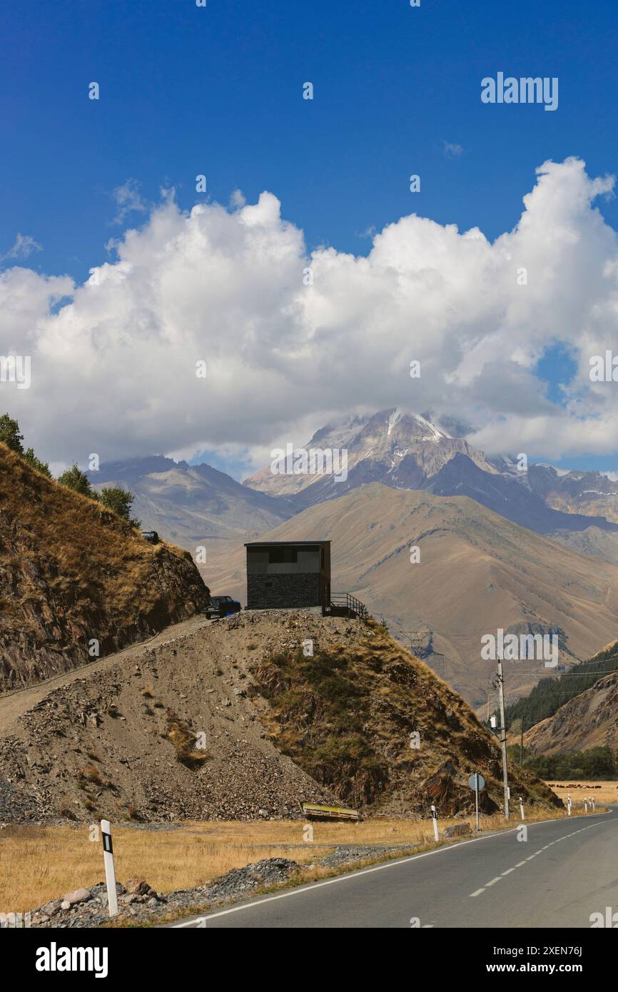 Itinéraire routier pittoresque avec vue sur les montagnes du Caucase sous des nuages cumulus bouillonnants et un ciel bleu avec côté, chemin de terre pour belvédère à Tru... Banque D'Images