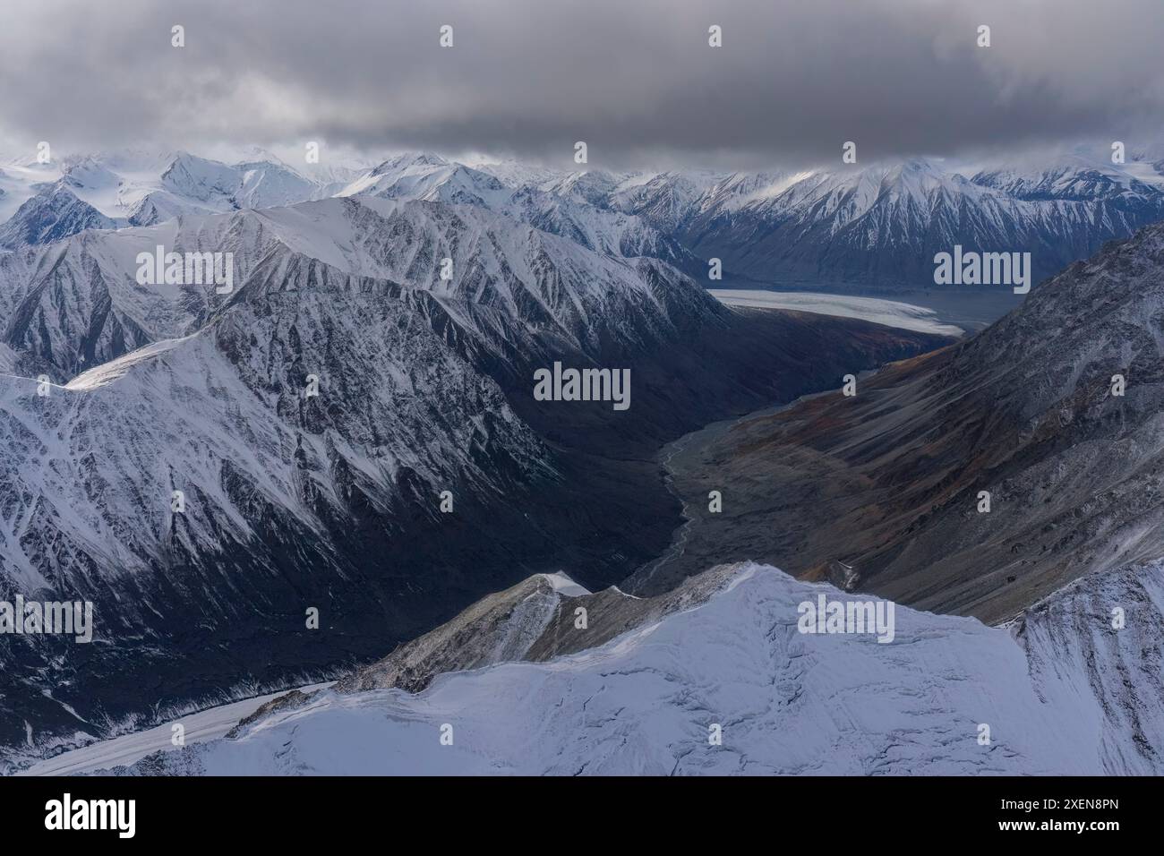 Vue aérienne des montagnes enneigées du parc national de Kluane sous des nuages gris, prise lors de la transition entre automne et hiver Banque D'Images