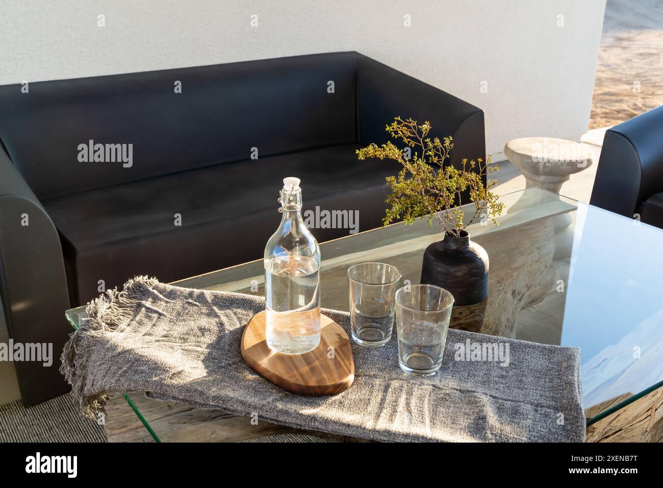 Table extérieure moderne verre bouteille d'eau verres et vase avec la lumière du soleil à Joshua Tree, Californie Banque D'Images