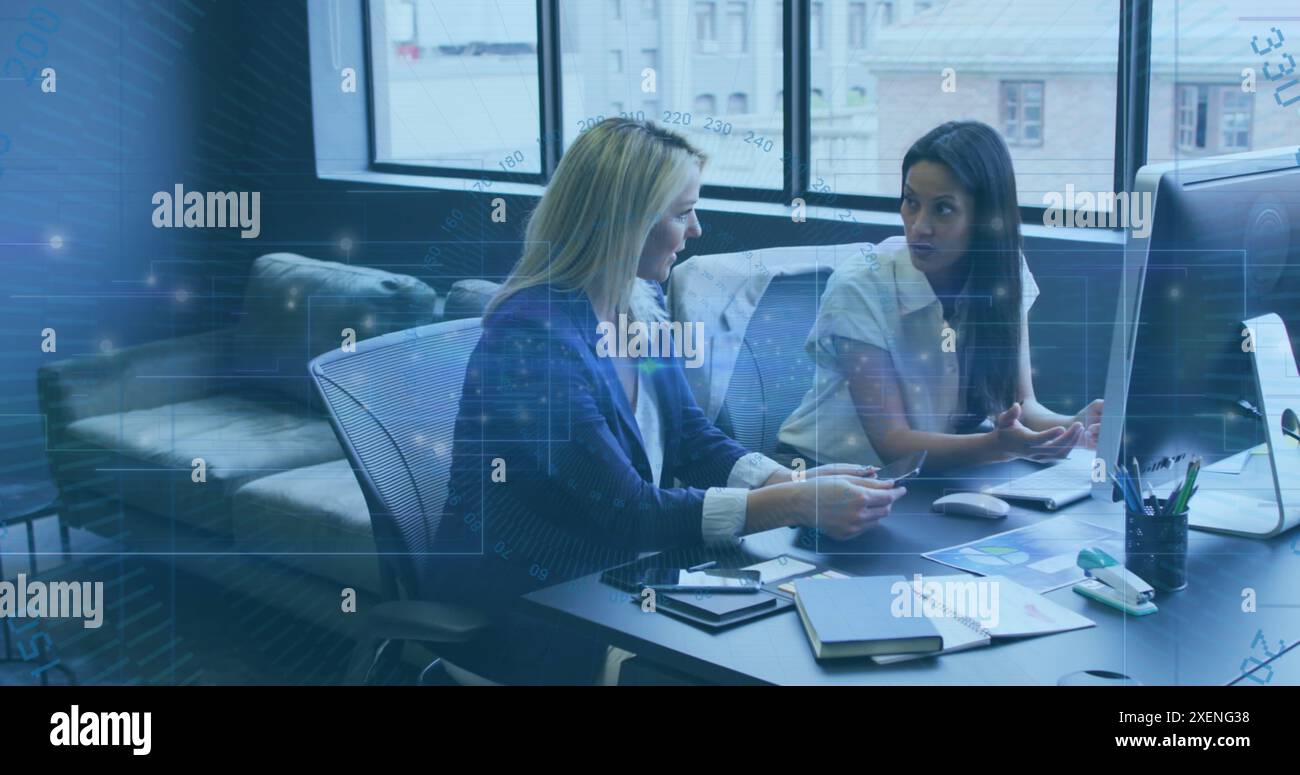 Image du traitement des données et des traînées de lumière contre deux femmes diverses discutant au bureau Banque D'Images