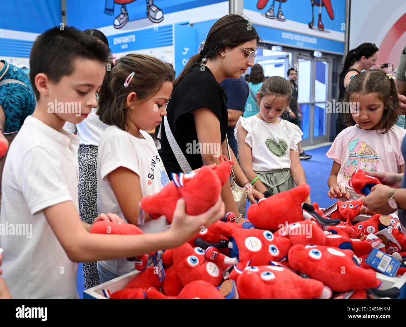 Paris, France. 27 juin 2024. Les clients achètent les produits des mascottes olympiques Phryges dans la boutique officielle Paris 2024 sur l'avenue des champs-Elysées à Paris, France, le 27 juin 2024. Crédit : HE Changshan/Xinhua/Alamy Live News Banque D'Images