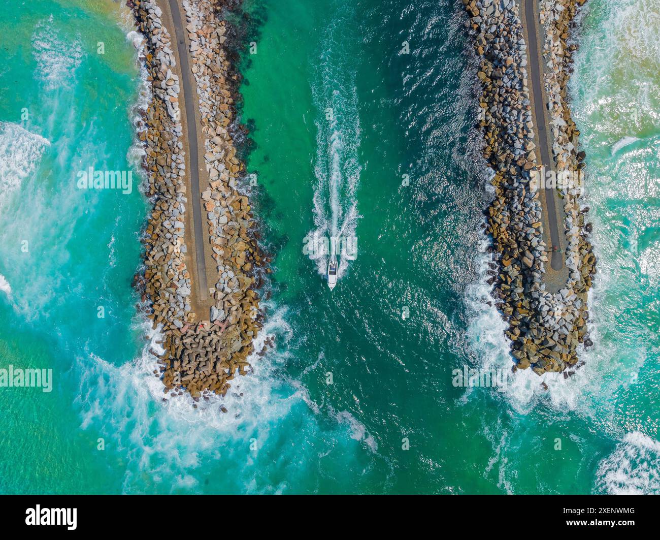 Vue aérienne d'un petit bateau se dirigeant vers la mer entre des murs brise-lames à Narooma sur la côte sud de la Nouvelle-Galles du Sud, Australie. Banque D'Images