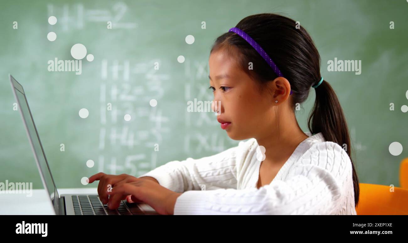 Image de points flottants fille asiatique tapant sur le clavier de l'ordinateur portable contre le tableau vert Banque D'Images