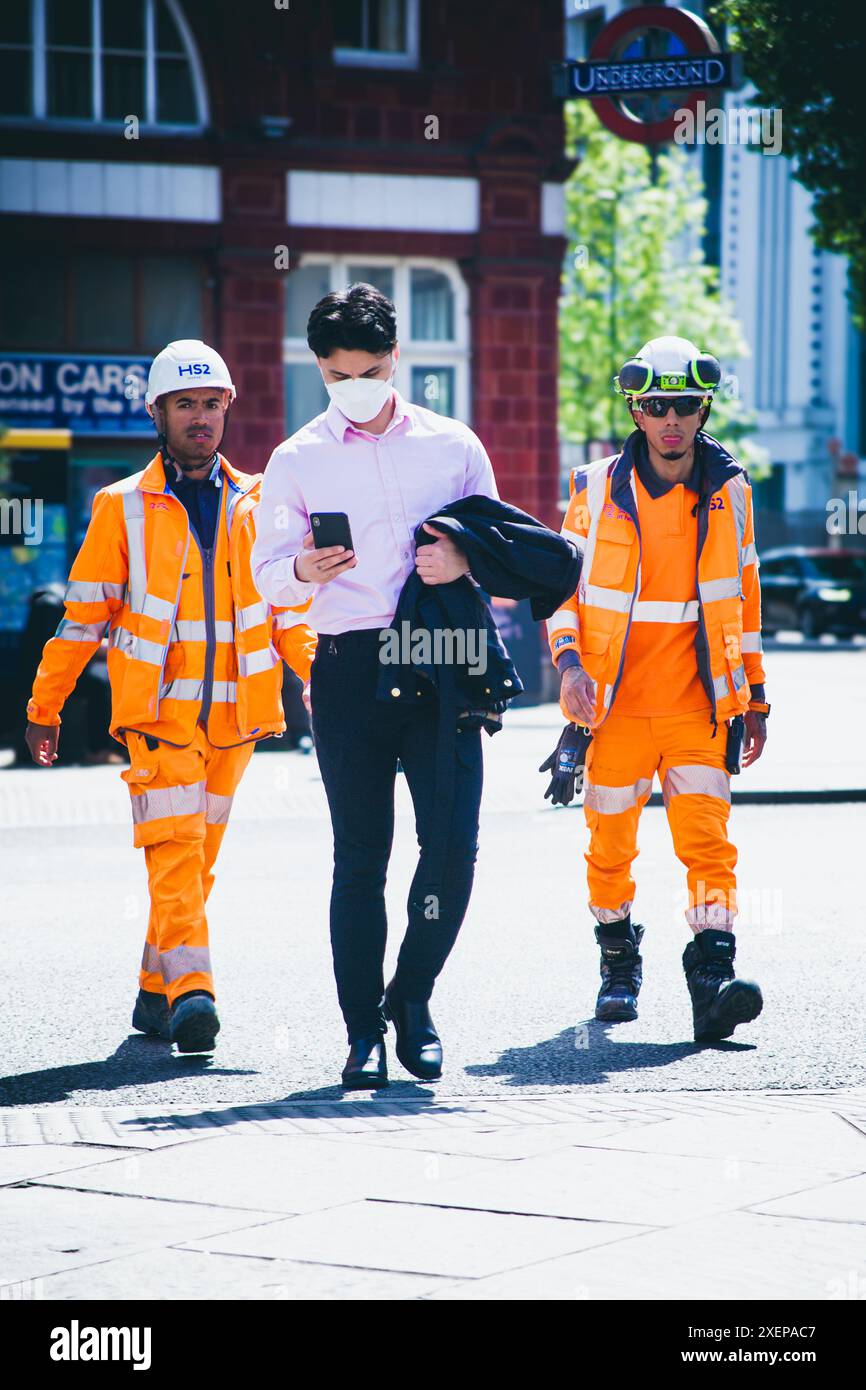 Aman traverse une route avec deux ouvriers de la construction juste derrière Banque D'Images