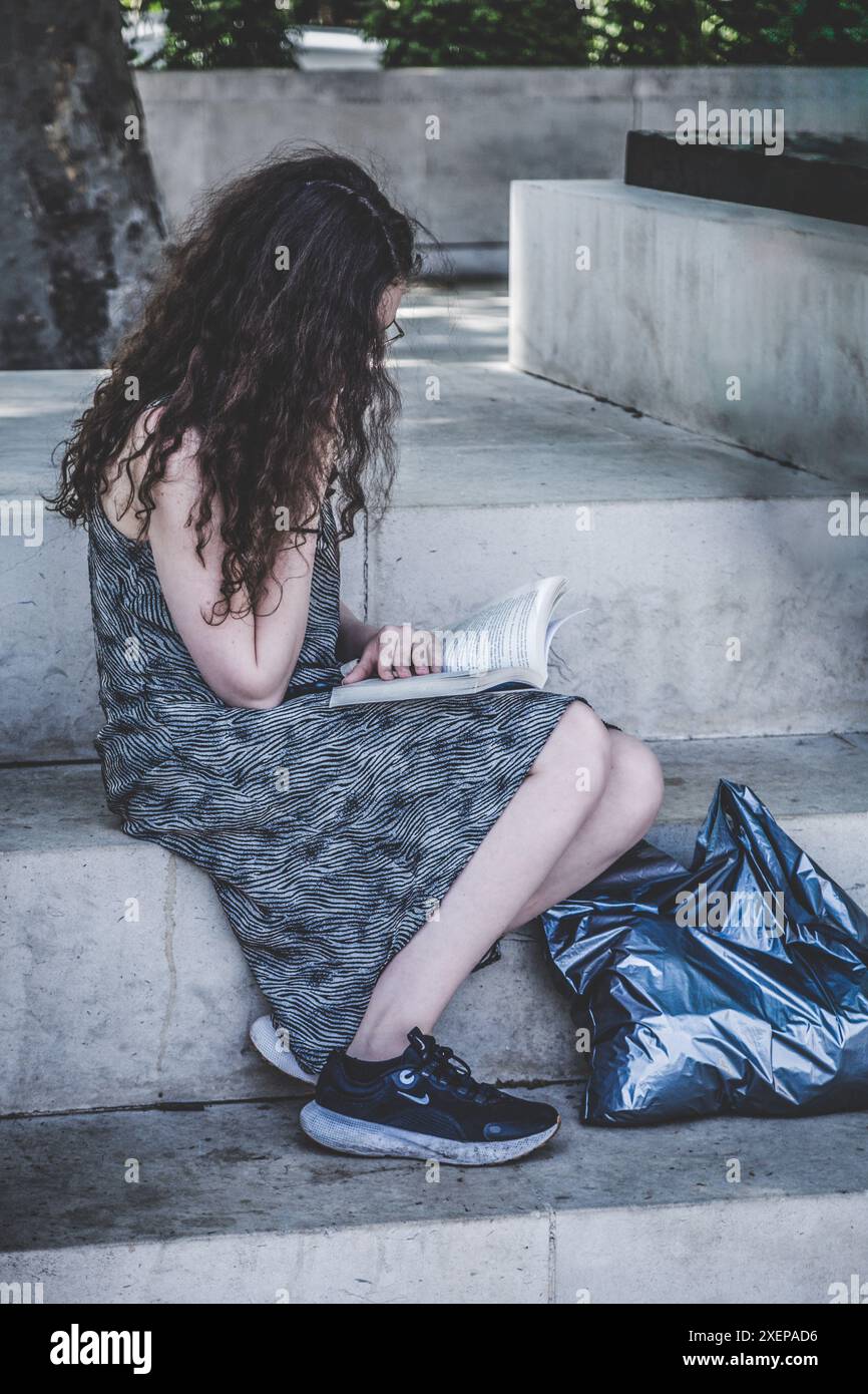 La femme est assise dehors et lit un livre à Westminster Banque D'Images