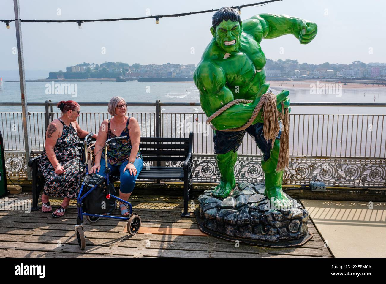 Deux femmes se reposant sur un banc à côté d'un modèle de l'incroyable Hulk, Paignton Pier, Devon Banque D'Images