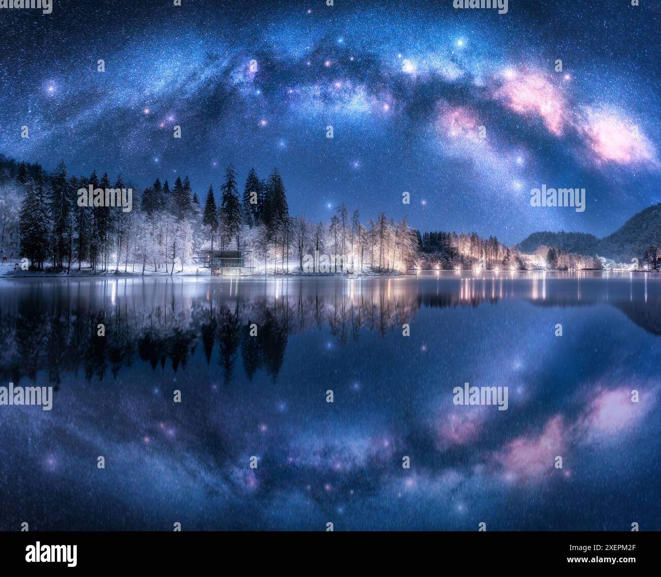 Arc de la voie lactée reflété dans l'eau à la nuit étoilée d'hiver. Paysage avec la voie lactée acrhed reflétée dans le lac de Bled, Slovénie. Ciel avec des étoiles brillantes, sno Banque D'Images