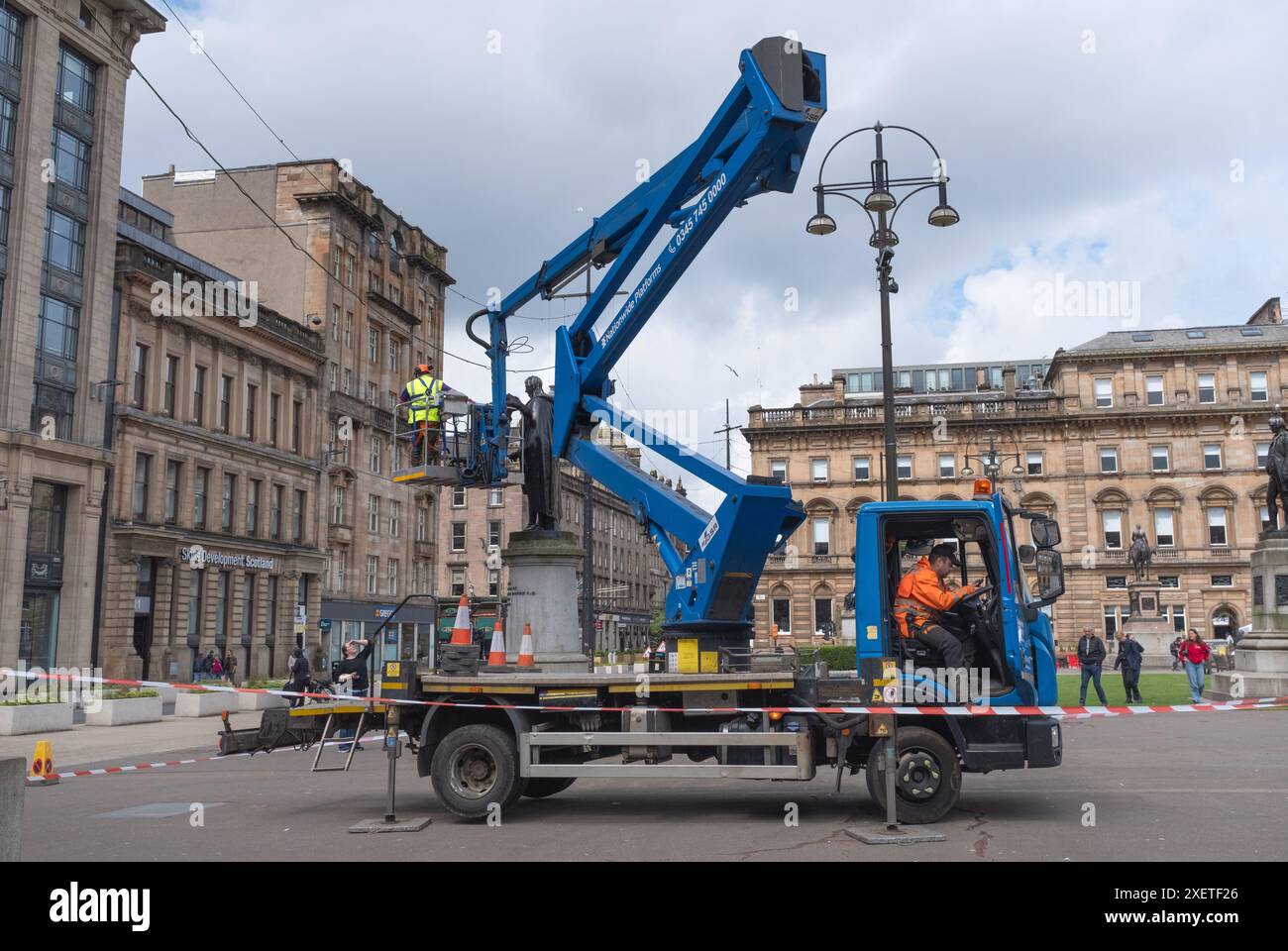 Les gens inspectent l'une des statues de George Square, dans le centre-ville de Glasgow, en Écosse, en utilisant un petit camion et une grue pour atteindre le haut. Banque D'Images