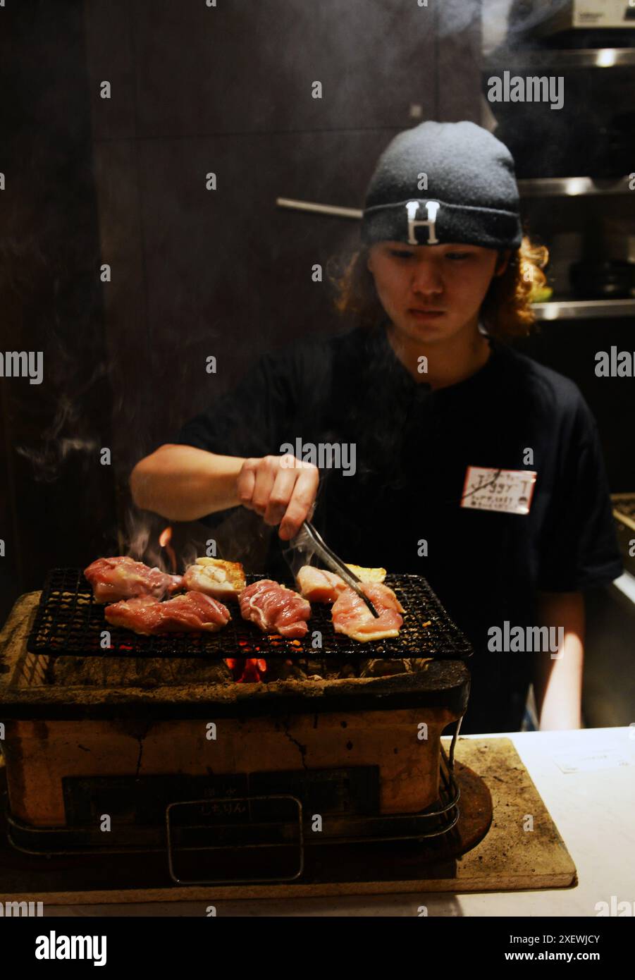 Un jeune japonais grillant des brochettes au restaurant Washio Yakitori Izakaya à Chuocho, Kagoshima, Japon. Banque D'Images