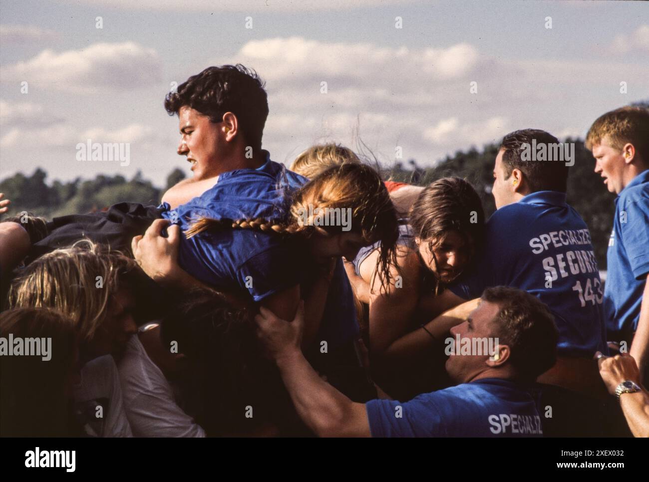 Reading, Royaume-Uni, août 1994 : le personnel de sécurité aide les spectateurs à franchir la barrière de la scène au Reading Festival en août 1994. Fondé sous le nom de National Jazz Festival en 1961, le festival a déménagé dans sa maison permanente à Little John's Farm à Reading en 1971 et a lieu pendant le week-end des vacances bancaires du Royaume-Uni en août. Banque D'Images