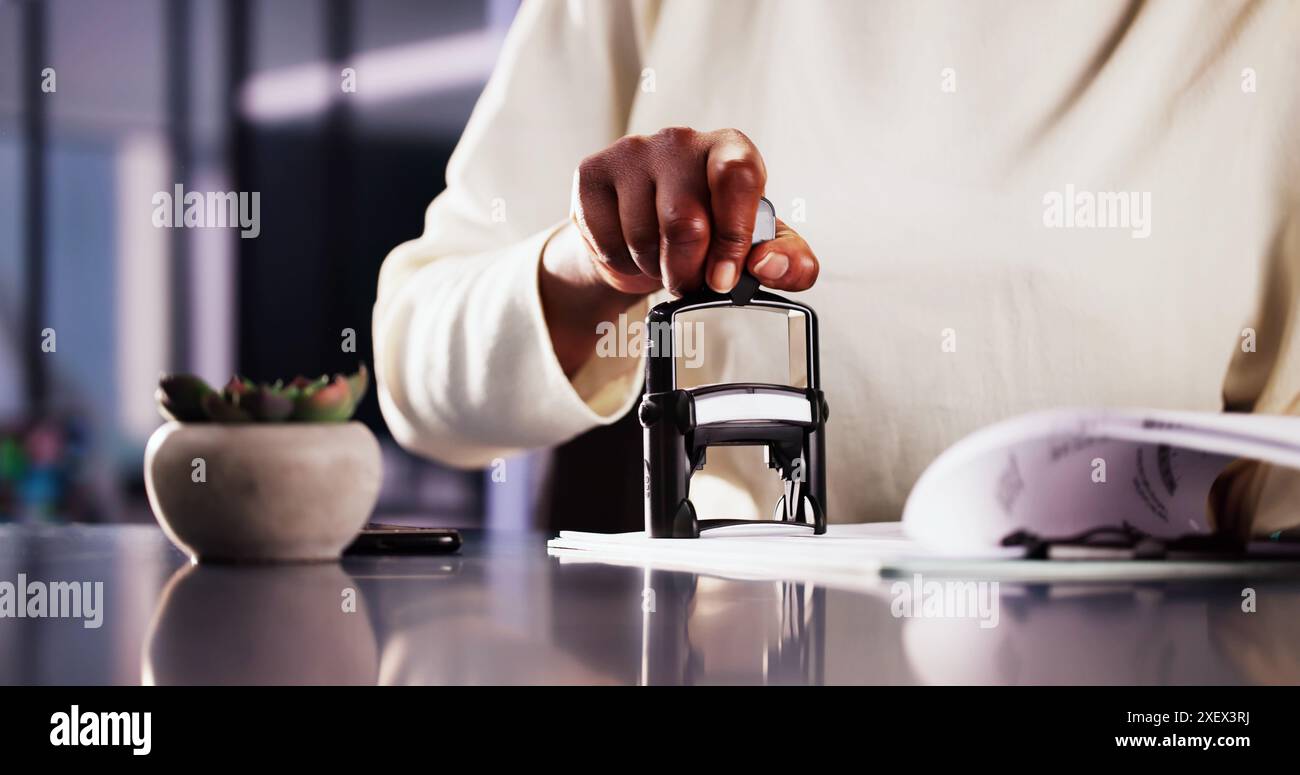 Femme d'affaires notariant des documents avec timbre dans le bureau : Assistant juridique approuvant les contrats pour la société afro-américaine utilisant le sceau officiel. Banque D'Images