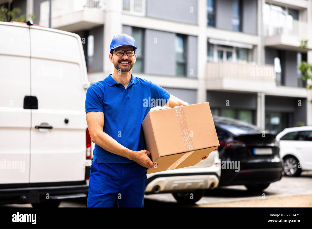 Smiling Delivery Man Moving Boxes by Van, montrant son expertise en logistique, expédition et distribution pour les opérations d'entrepôt commercial. Banque D'Images