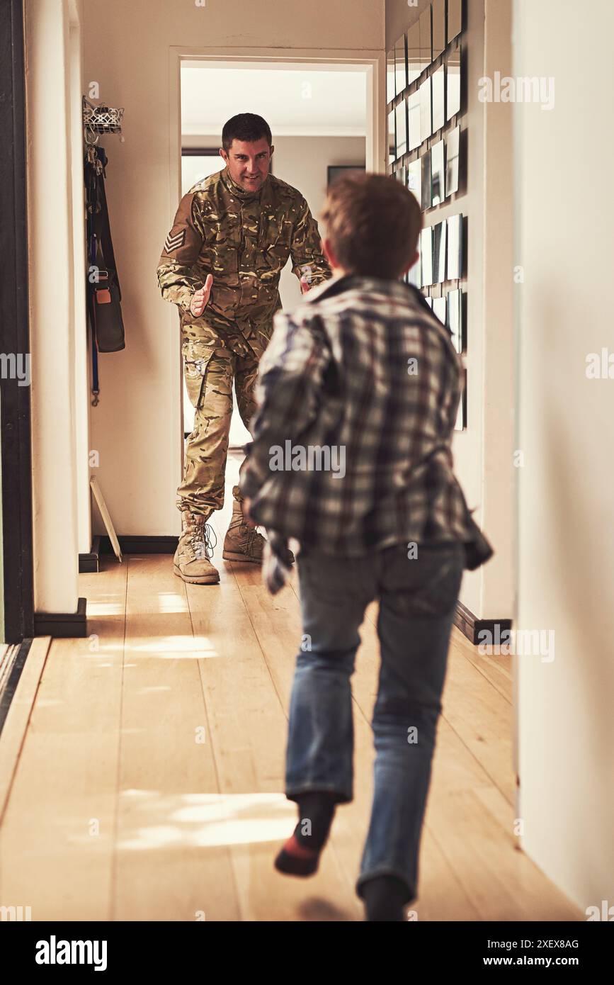 Père, soldat et enfant courant dans le couloir pour accueillir à la maison, bonjour et excité pour la famille. Homme militaire ou amour, fils et salut ou câlin à l'avant Banque D'Images