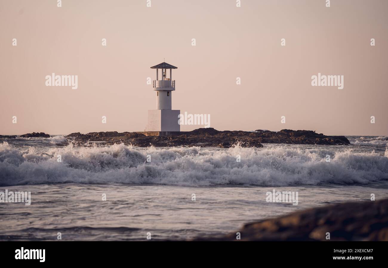 Phare entouré d'eau et ciel nuageux coucher de soleil Banque D'Images