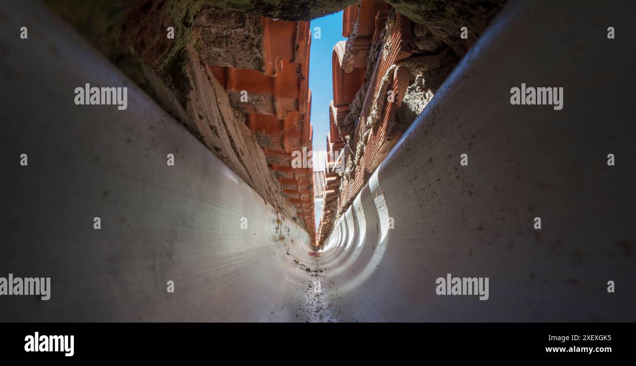 Intérieur d'une gouttière en PVC à la confluence d'un toit à pignon. vision tunnel Banque D'Images