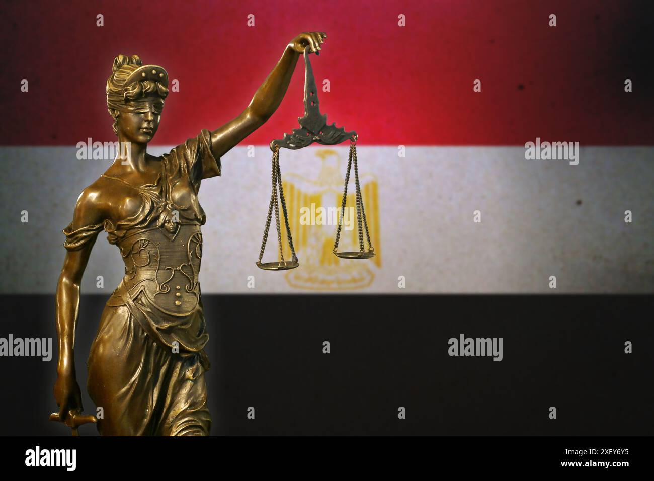 Gros plan d'une petite statuette en bronze de Dame Justice devant un drapeau égyptien. Banque D'Images