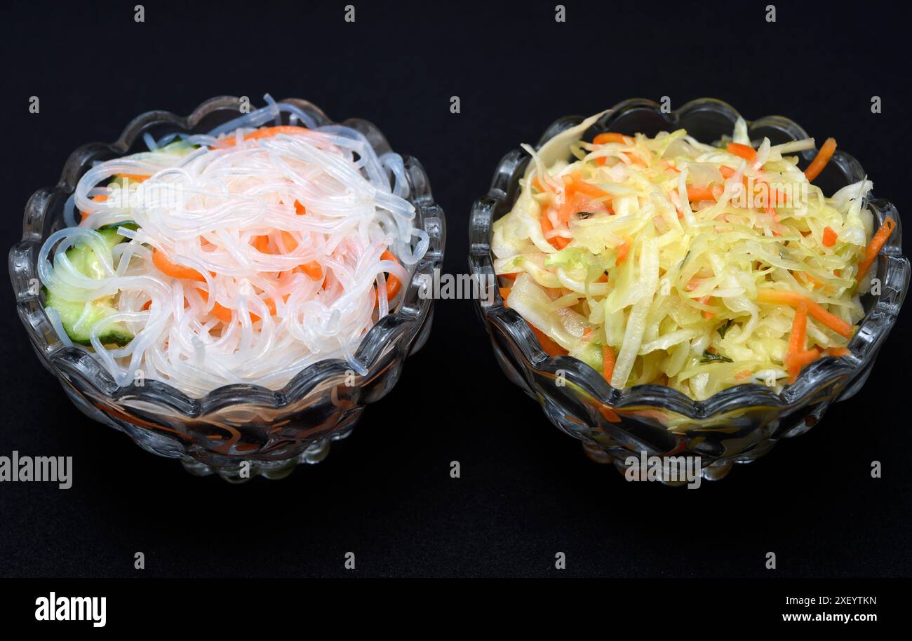 Salade de légumes dans un saladier en verre sur fond noir. Une portion de salade de légumes et nouilles coréennes funchese. Banque D'Images