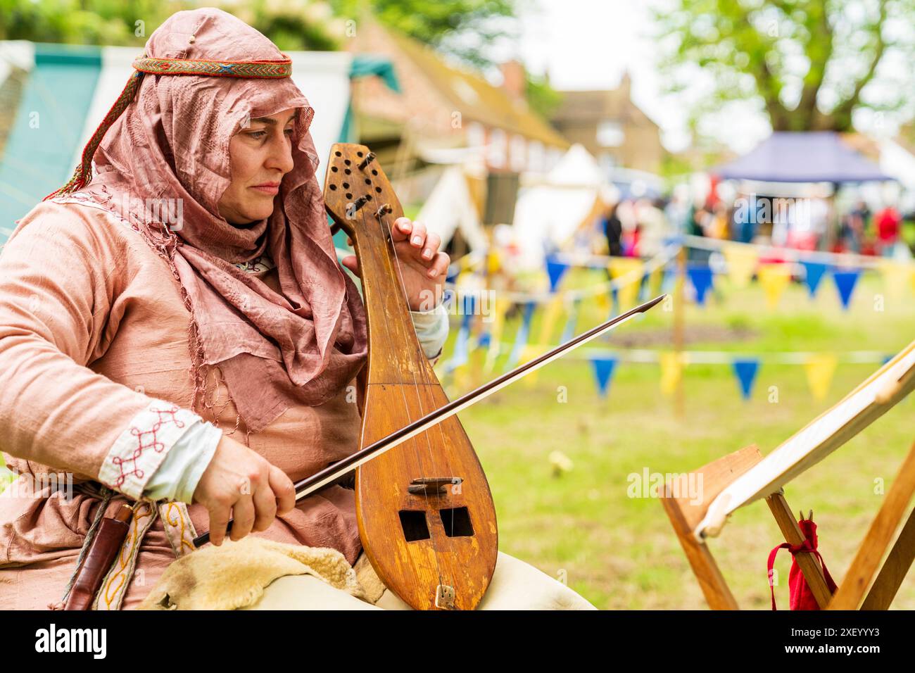 Gros plan d'une femme vêtue d'un costume médiéval assise et jouant une lyre byzantine également connue sous le nom de lira, avec un stand de musique devant elle. Banque D'Images