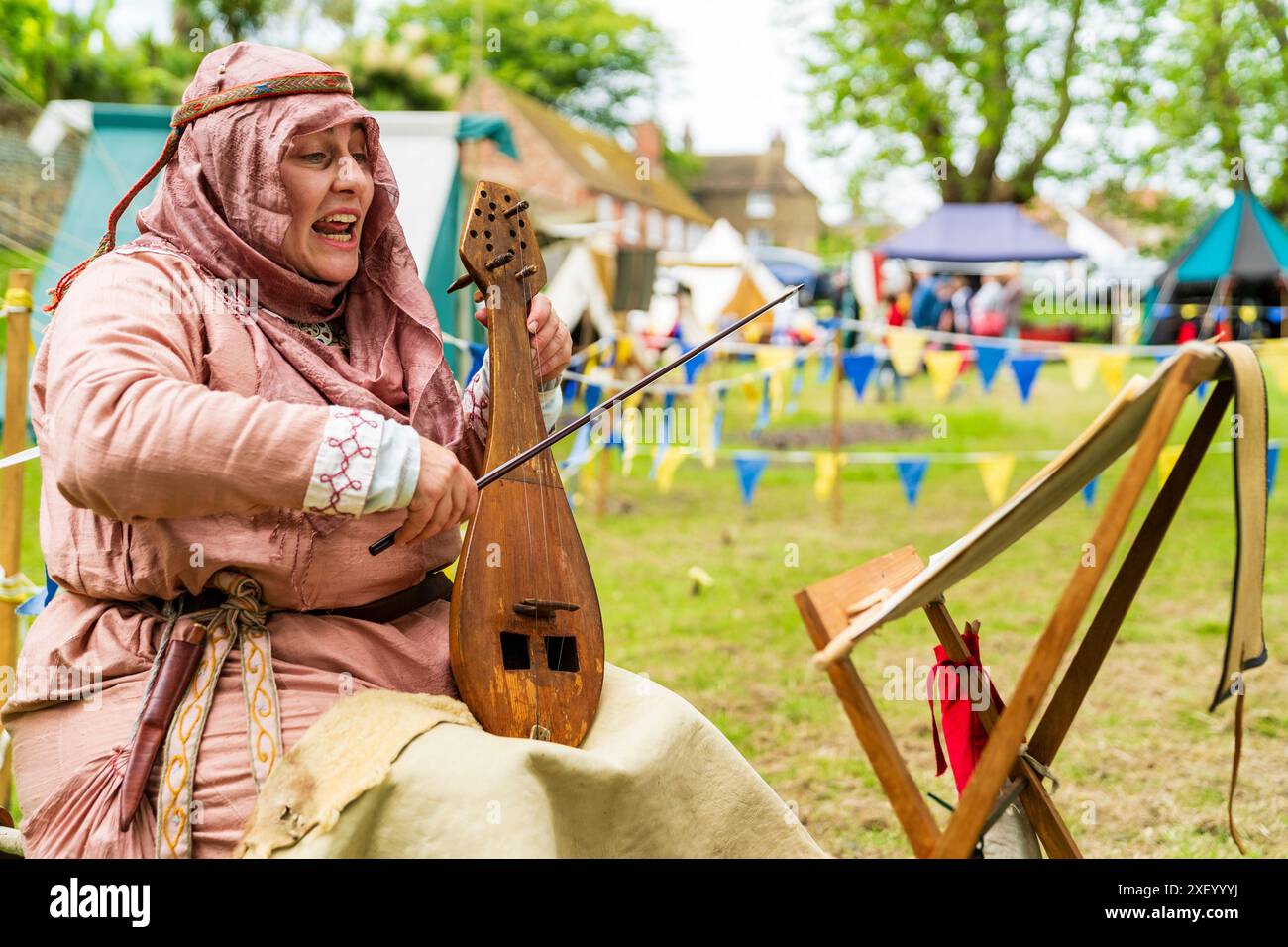 Gros plan d'une femme vêtue d'un costume médiéval chantant et jouant une lyre byzantine également connue sous le nom de lira, avec un stand de musique devant elle. Banque D'Images