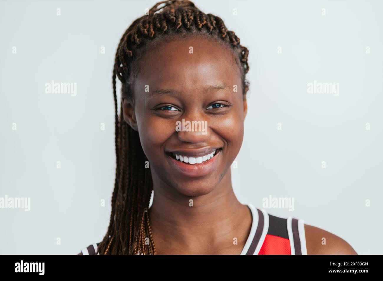 Photo gros plan portrait d'une jeune femme dans un uniforme de basket rouge souriant. L'image capture son énergie positive et son enthousiasme, mettant en valeur le JO Banque D'Images