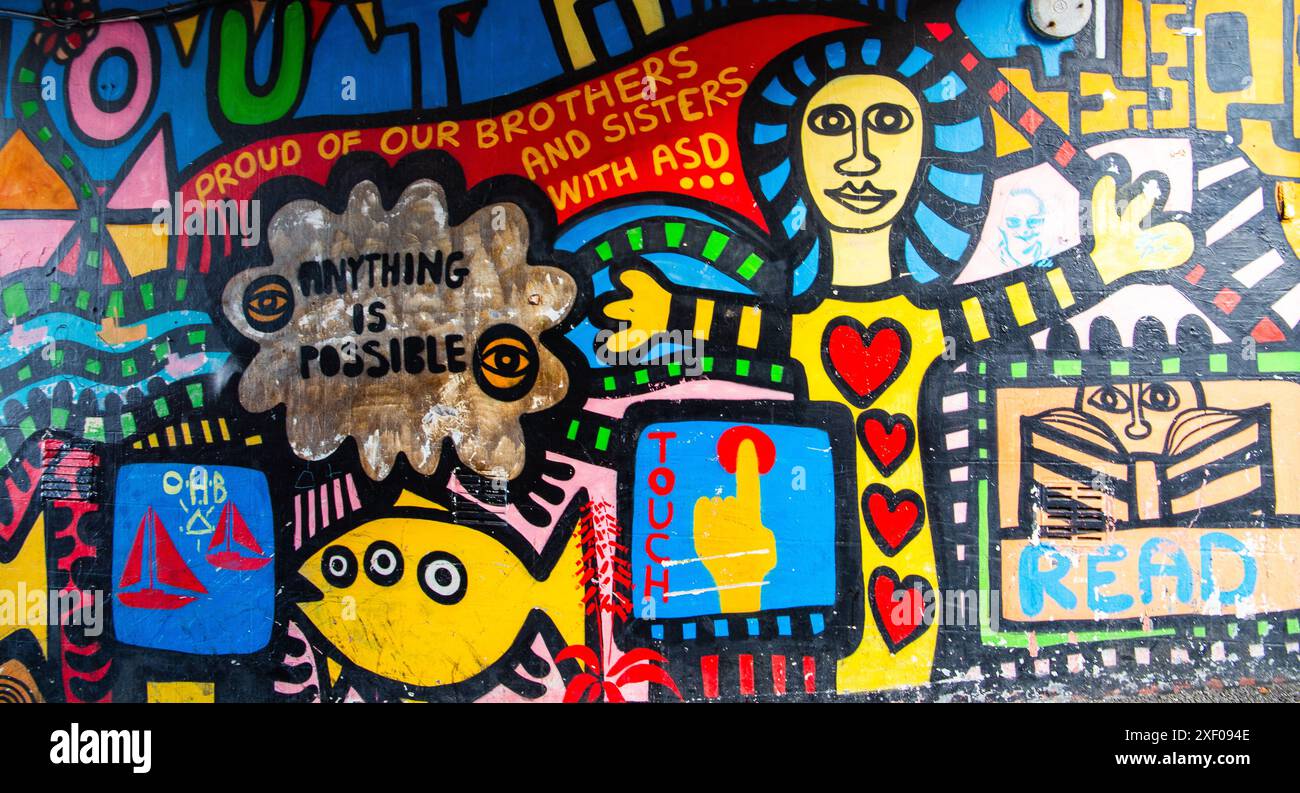 Murale colorée d'art de rue avec des messages inspirants, des symboles et des figures abstraites sur un mur en bas d'une rue latérale Falmouth Cornwall UK Banque D'Images