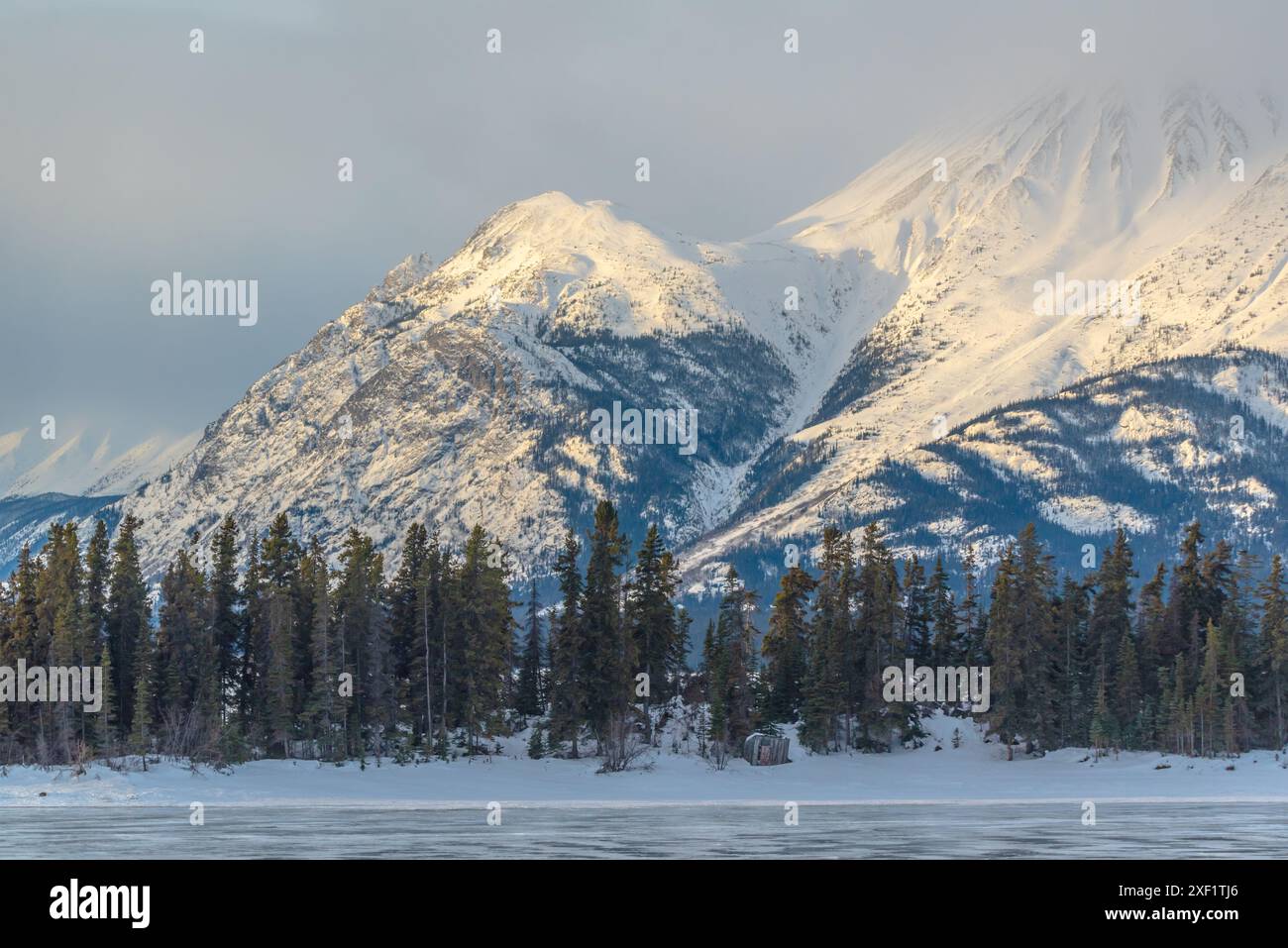 Incroyables montagnes enneigées en hiver avec un lac gelé au premier plan. Prise à Atlin, en Colombie-Britannique, près de l'Alaska, territoire du Yukon. Banque D'Images